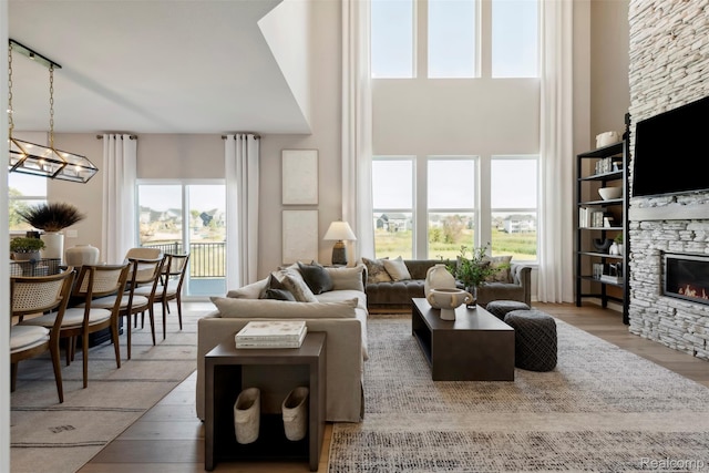 873 Risdon Trl S, Saline, MI 48176 - living room featuring a stone fireplace, wood finished floors, healthy amount of natural light, a towering ceiling, and a chandelier