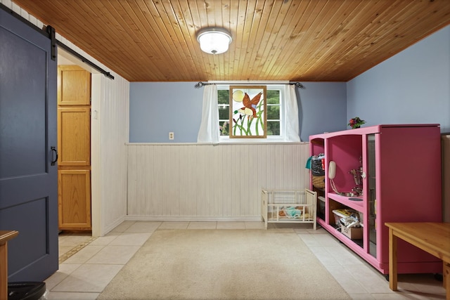 5852 Pinkerton Rd, Vassar, MI 48768 - playroom featuring tile patterned flooring, wooden ceiling, wainscoting, a barn door, and wood walls