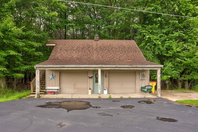 5852 Pinkerton Rd, Vassar, MI 48768 - view of front of property featuring a chimney, a shingled roof, a garage, board and batten siding, and view of scattered trees
