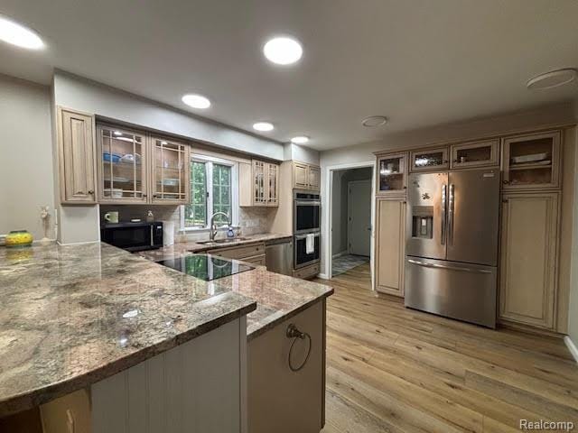 171 Golfview Dr, Caro, MI 48723 - kitchen featuring appliances with stainless steel finishes, a peninsula, light wood-style flooring, light stone counters, and glass insert cabinets