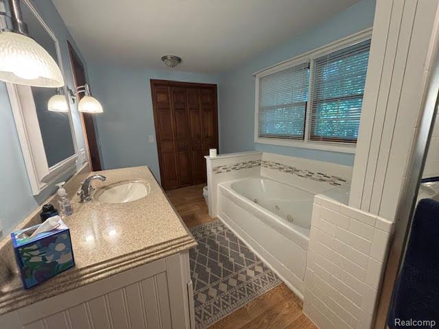 171 Golfview Dr, Caro, MI 48723 - bathroom with vanity, a whirlpool tub, and wood finished floors