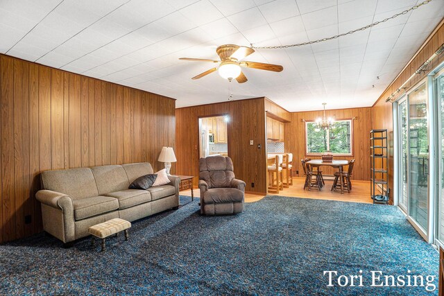 4366 Woods Rd, Sidney, MI 48885 - carpeted living area with wooden walls, a chandelier, and a ceiling fan