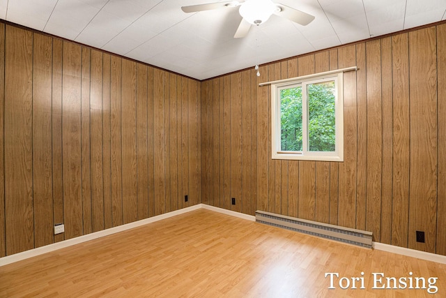 4366 Woods Rd, Sidney, MI 48885 - unfurnished room with a baseboard radiator, wood finished floors, ceiling fan, and wood walls