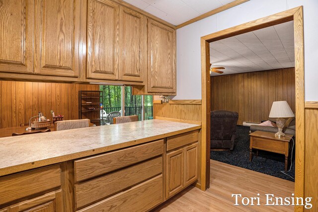 4366 Woods Rd, Sidney, MI 48885 - kitchen with wooden walls, light countertops, light wood finished floors, a ceiling fan, and brown cabinets
