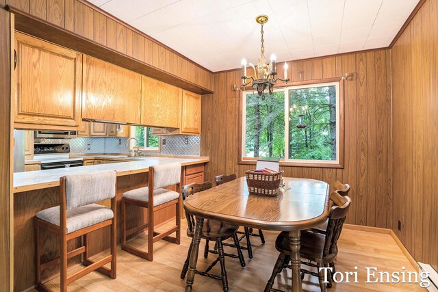 4366 Woods Rd, Sidney, MI 48885 - dining room featuring a chandelier, wood walls, and light wood-style flooring