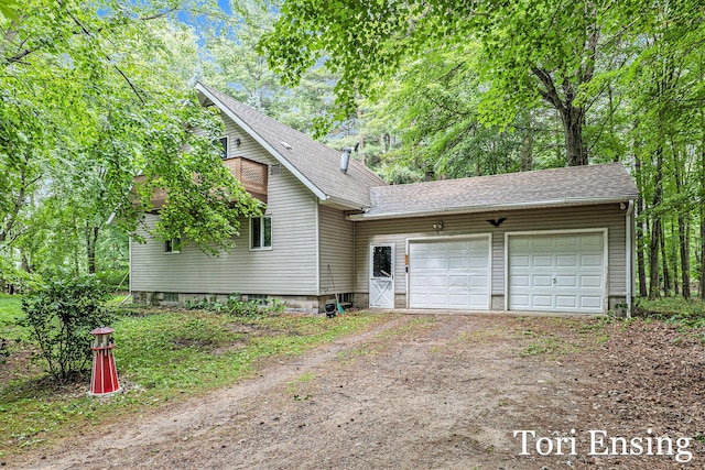 4366 Woods Rd, Sidney, MI 48885 - view of side of home featuring driveway, an attached garage, and roof with shingles