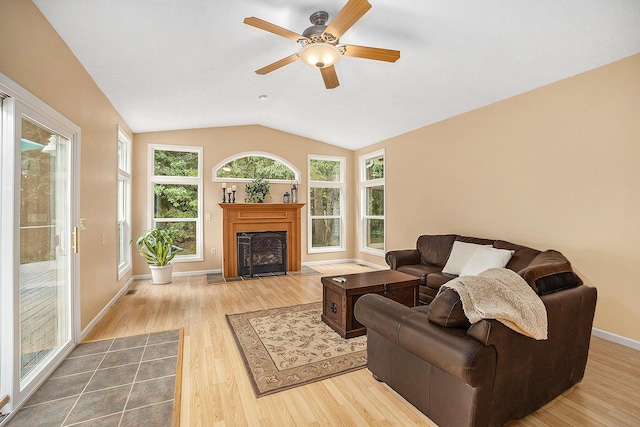 308 N Thomas St, Scottville, MI 49454 - living area featuring wood finished floors, a fireplace with flush hearth, ceiling fan, and vaulted ceiling