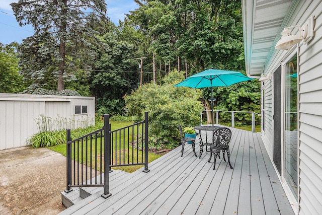 308 N Thomas St, Scottville, MI 49454 - wooden deck featuring view of wooded area, a lawn, and outdoor dining area