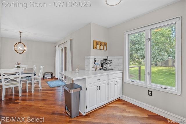220 E Rolston Rd, Linden, MI 48451 - kitchen featuring a chandelier, light wood-style flooring, light countertops, white cabinets, and decorative backsplash