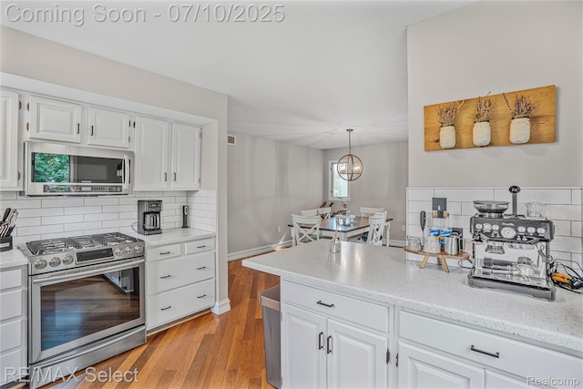 220 E Rolston Rd, Linden, MI 48451 - kitchen featuring appliances with stainless steel finishes, decorative backsplash, light wood-style floors, and white cabinets
