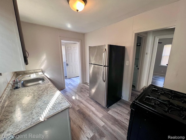 7511 Orchard Ave, Warren, MI 48091 - kitchen featuring freestanding refrigerator, gas stove, light wood-style floors, and light countertops