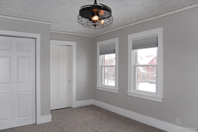 unfurnished dining area with carpet, ornamental molding, and a textured ceiling