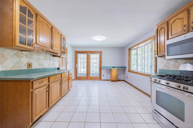 21128 Middlebelt Rd, New Boston, MI 48164 - kitchen featuring range with gas cooktop, stainless steel microwave, glass insert cabinets, tasteful backsplash, and brown cabinets