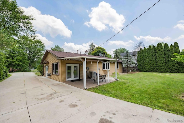21128 Middlebelt Rd, New Boston, MI 48164 - rear view of property featuring french doors, driveway, a yard, and a patio area
