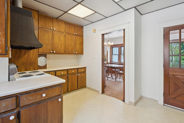 418 Main St, Battle Creek, MI 49014 - kitchen featuring exhaust hood, a chandelier, light countertops, light flooring, and brown cabinetry