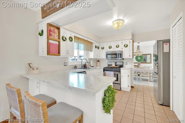 46655 Spruce Dr, Shelby Twp, MI 48315 - kitchen featuring appliances with stainless steel finishes, a peninsula, white cabinets, light tile patterned floors, and a kitchen breakfast bar