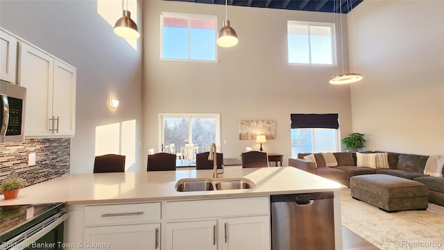 293 N 2nd St Unit 106, Brighton, MI 48116 - kitchen featuring appliances with stainless steel finishes, open floor plan, a towering ceiling, white cabinetry, and a peninsula