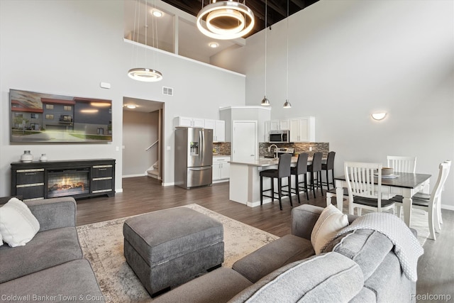 293 N 2nd St Unit 106, Brighton, MI 48116 - living room featuring a high ceiling, stairway, dark wood finished floors, and a glass covered fireplace