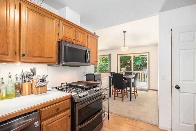 15303 Arborwood Dr, Grand Haven, MI 49417 - kitchen with appliances with stainless steel finishes, brown cabinetry, light countertops, light wood-type flooring, and decorative light fixtures