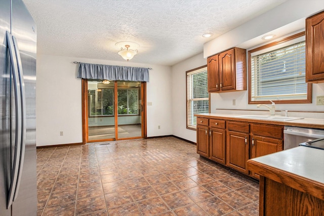 9477 Lightwood Ct, Richland, MI 49083 - kitchen with appliances with stainless steel finishes, brown cabinets, light countertops, and a textured ceiling