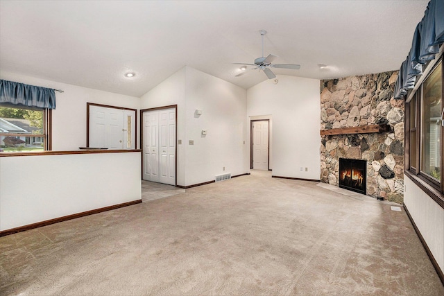 9477 Lightwood Ct, Richland, MI 49083 - unfurnished living room featuring a ceiling fan, vaulted ceiling, a stone fireplace, and light colored carpet