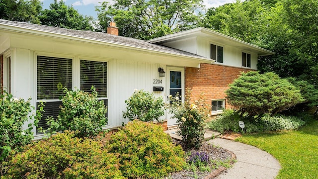 2204 Walter Dr, Ann Arbor, MI 48103 - view of exterior entry featuring a chimney, brick siding, and roof with shingles
