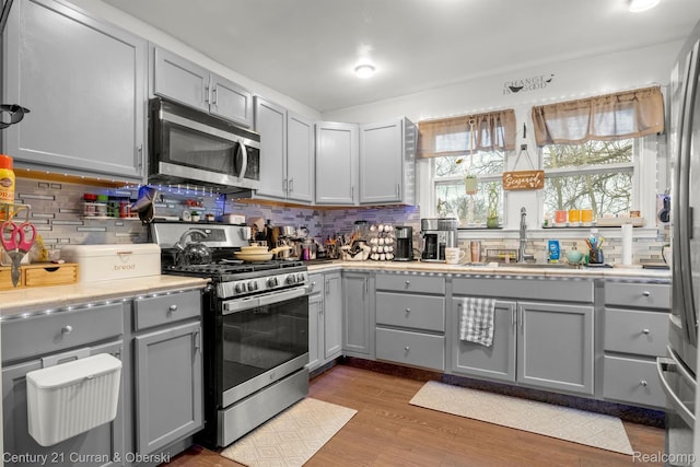 25021 Ecorse Rd, Taylor, MI 48180 - kitchen with stainless steel appliances, gray cabinets, decorative backsplash, light countertops, and wood finished floors