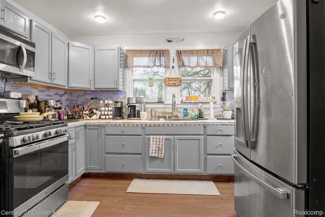 25021 Ecorse Rd, Taylor, MI 48180 - kitchen featuring stainless steel appliances, decorative backsplash, light countertops, light wood-style flooring, and gray cabinetry