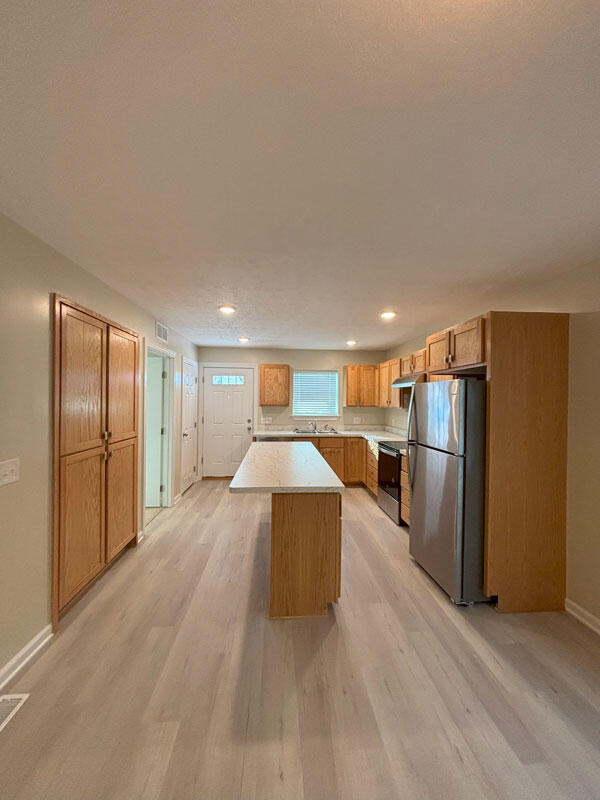 436 Martin Luther King Jr St SE, Grand Rapids, MI 49507 - kitchen featuring freestanding refrigerator, a kitchen island, light wood-style flooring, stove, and light countertops