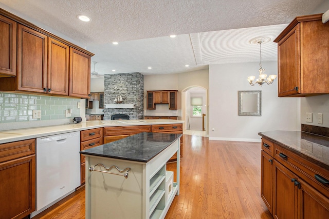4785 Cottagewood Dr, Kalamazoo, MI 49048 - kitchen with dishwasher, a textured ceiling, backsplash, brown cabinetry, and a chandelier