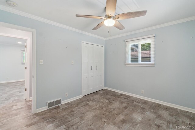 7262 Hatchery Rd, Waterford, MI 48327 - unfurnished bedroom with multiple windows, wood finished floors, crown molding, a closet, and ceiling fan