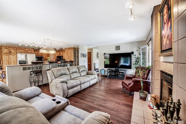 24559 S Klingville Rd, Chassell, MI 49916 - living room featuring track lighting, dark wood finished floors, a fireplace, and a chandelier