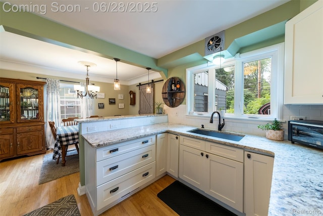 31718 W Chicago St, Canton, MI 48150 - kitchen featuring light wood-style flooring, white cabinetry, a chandelier, a peninsula, and tasteful backsplash