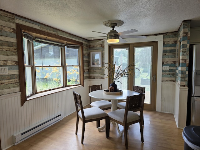1236 Klink Rd, Tekonsha, MI 49092 - dining area featuring a baseboard heating unit, wooden walls, light wood-style floors, plenty of natural light, and a wainscoted wall