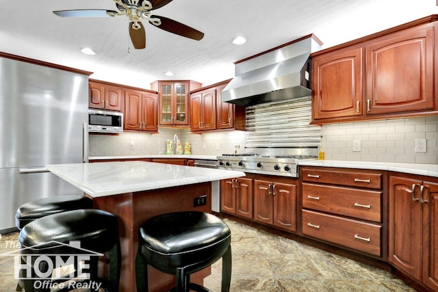 2367 Meadowdown Dr, Owosso, MI 48867 - kitchen with stainless steel appliances, wall chimney exhaust hood, a breakfast bar area, ceiling fan, and tasteful backsplash