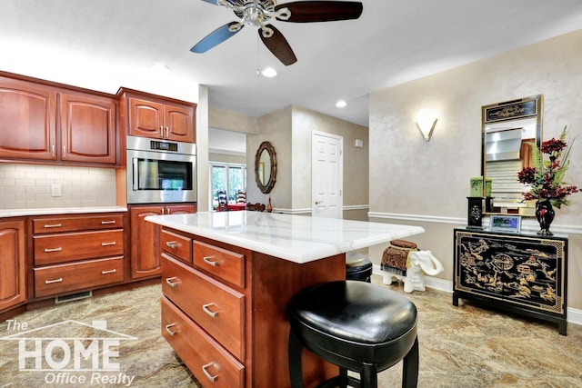 2367 Meadowdown Dr, Owosso, MI 48867 - kitchen with oven, a ceiling fan, light countertops, a breakfast bar, and a kitchen island