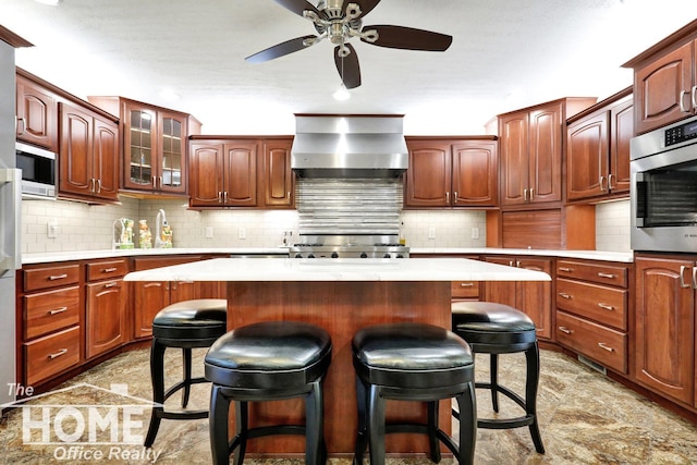 2367 Meadowdown Dr, Owosso, MI 48867 - kitchen featuring wall chimney exhaust hood, a breakfast bar, light countertops, ceiling fan, and stove