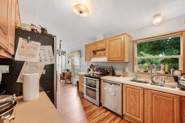 733 N Main St, Evart, MI 49631 - kitchen with appliances with stainless steel finishes, light countertops, a textured ceiling, light wood finished floors, and under cabinet range hood