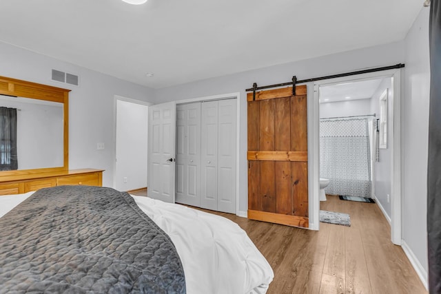 2151 Glenwood Ct, Brooklyn, MI 49230 - bedroom with light wood finished floors, a closet, ensuite bath, and a barn door