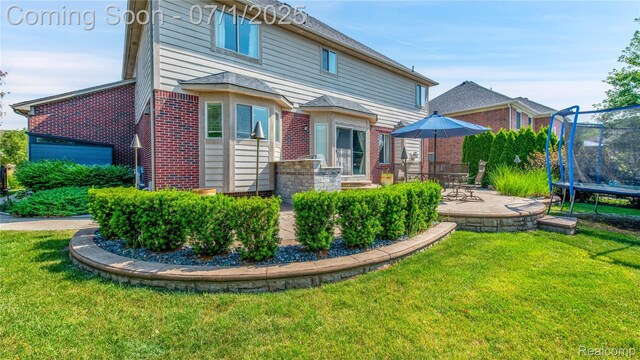 19492 Springbrook Dr, Macomb, MI 48044 - back of house featuring brick siding, a trampoline, a patio area, and a yard