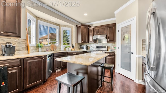 19492 Springbrook Dr, Macomb, MI 48044 - kitchen with appliances with stainless steel finishes, ornamental molding, under cabinet range hood, a kitchen bar, and dark wood finished floors