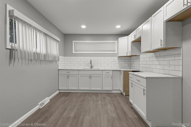 1587 Reo Ave, Lincoln Park, MI 48146 - kitchen featuring light wood finished floors, backsplash, light countertops, recessed lighting, and white cabinetry