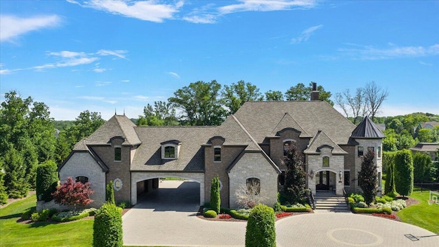1988 Christenbury Ct, Rochester, MI 48306 - french country inspired facade with stone siding, curved driveway, and a chimney