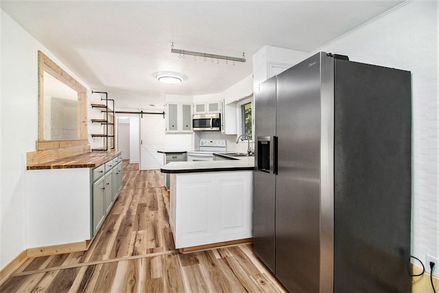 1722 Benson, Fountain, MI 49410 - kitchen with appliances with stainless steel finishes, a barn door, light wood finished floors, white cabinets, and a peninsula