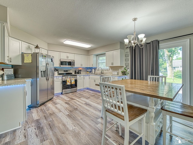 8299 Galloway Dr, Lambertville, MI 48144 - kitchen with stainless steel appliances, light countertops, a chandelier, a textured ceiling, and light wood-style flooring