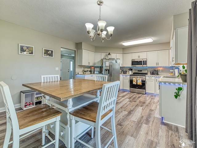 8299 Galloway Dr, Lambertville, MI 48144 - dining area featuring a chandelier, light wood-style floors, and a textured ceiling