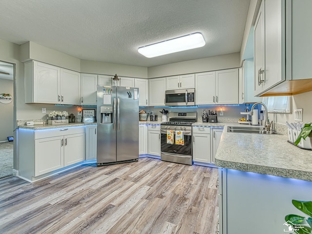 8299 Galloway Dr, Lambertville, MI 48144 - kitchen with appliances with stainless steel finishes, light wood finished floors, a textured ceiling, light countertops, and white cabinets
