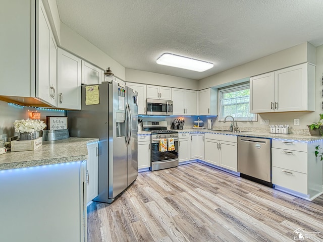 8299 Galloway Dr, Lambertville, MI 48144 - kitchen with appliances with stainless steel finishes, a textured ceiling, light wood finished floors, light countertops, and white cabinets