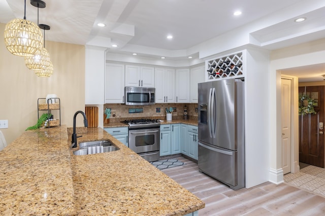 464 Kalamazoo St, South Haven, MI 49090 - kitchen with stainless steel appliances, a raised ceiling, light wood-style floors, light stone counters, and backsplash