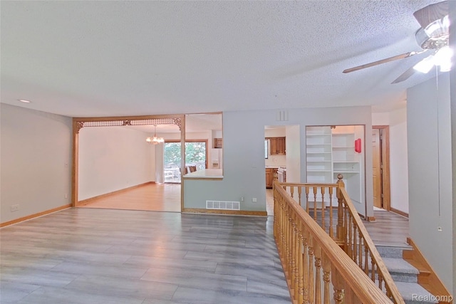 11589 Lombardy Ct, Pinckney, MI 48169 - empty room with a chandelier, ceiling fan, a textured ceiling, and wood finished floors